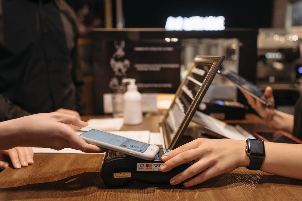 about-us-01 Hands using mobile for contactless payment at café terminal.